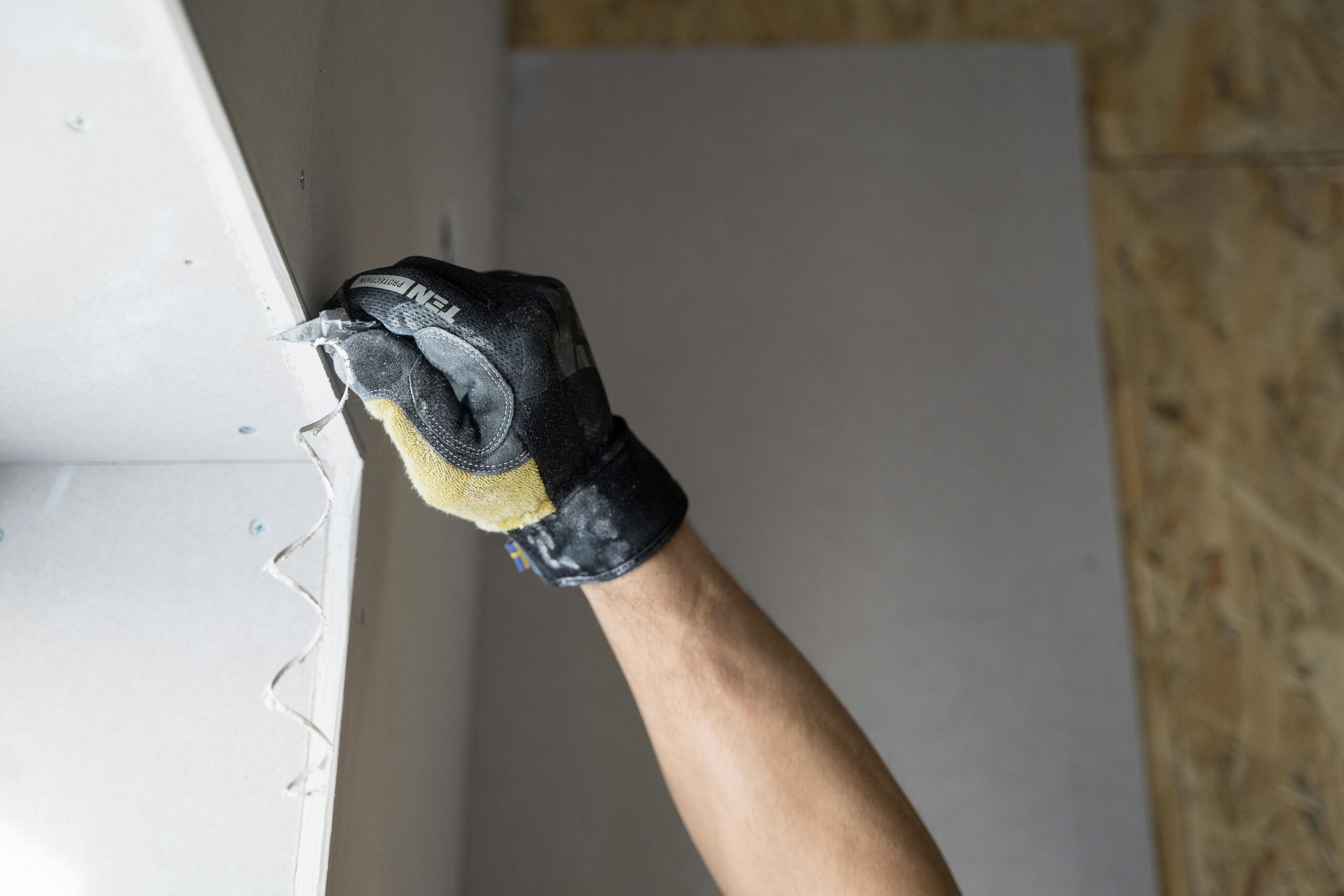 Close-up of a gloved hand applying plaster to a wall indoors in Falun, Sweden.
